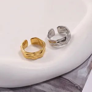 Detail view of irregular geometric open rings in gold and silver with wave texture