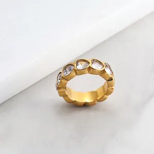 Close-up of wide gold ring with sparkling heart-shaped cubic zirconia stones