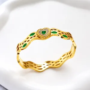 Detailansicht eines goldenen Wellenarmreifs mit grünem Herzstein und Zirkonia-Besatz