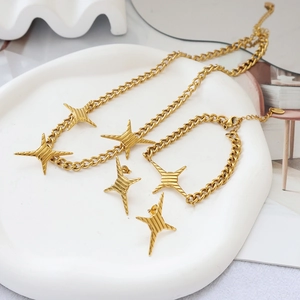 Nahaufnahme von goldenem Stern-Schmuckset mit Panzerketten auf weißem Keramiktablett