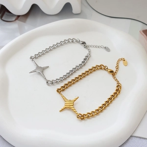 Detail von gold- und silberfarbenen Stern-Armbändern mit Gliederkette auf Tablett