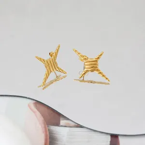 Detailansicht der goldenen Sternohrringe mit Rippentextur auf einer Spiegelfläche