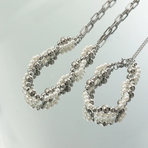 Dettaglio di una collana di perle a strati con moderne maglie di catena in metallo argento