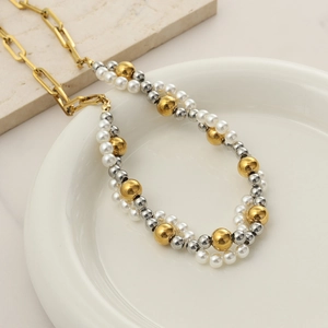 Dettaglio della collana a doppio strato con perle finte miste su piatto di ceramica