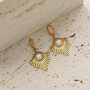 Macro view of golden U-shaped earrings featuring a radial sunburst pattern and white pearl