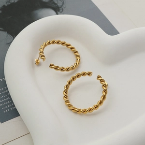 Classic golden twisted hoop earrings with a woven rope design in a heart ceramic tray