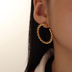 Gold twisted rope hoop earring shown on ear with a classic woven metallic texture