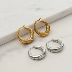 Minimalist U-shaped stainless steel gold hoop earrings with twisted texture on marble