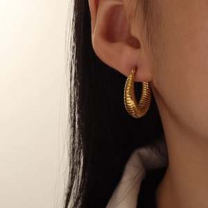 Minimalist 18K gold U-shape hoop earrings with spiral texture shown on model ear