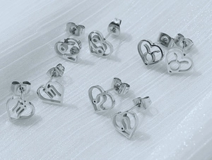 Detail view of heart-shaped stainless steel zodiac stud earrings with cancer and leo signs