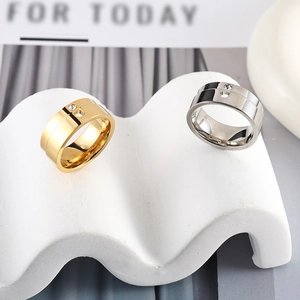 Macro shot of polished gold and silver waterdrop rings with zircon on a wavy stand