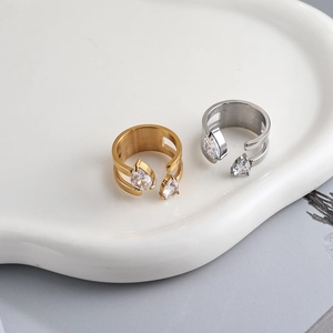 Elegant gold and silver open rings with pear-cut cubic zirconia on a ceramic tray