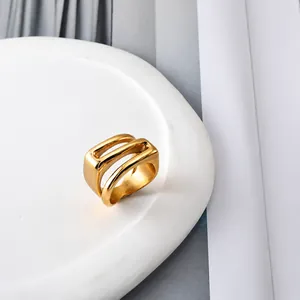 Detailansicht eines breiten, goldenen Lagenrings auf einer weißen Keramikschale