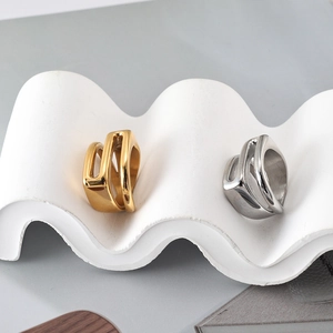 Makroaufnahme geometrischer Gold- und Silberringe auf einem Wellen-Skulpturenständer