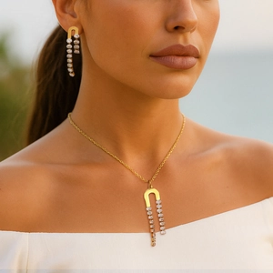Elegant gold U-shape horseshoe necklace and earring set with shimmering zircon tassels