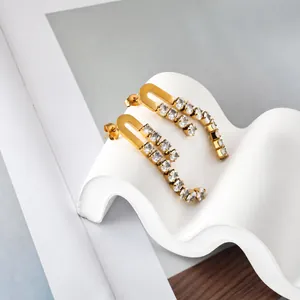 Detail of long gold earrings with tassel crystal zircons on a wavy white stand