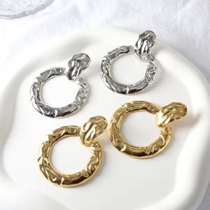 Two-tone geometric hoop earrings with hammered texture on minimalist display