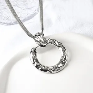 Detailed macro of a silver lava-style irregular ring pendant on a fine snake chain necklace