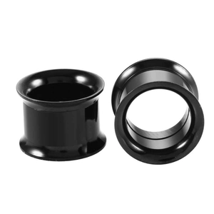 Macro view of black stainless steel ear tunnels showing hollow center and side groove