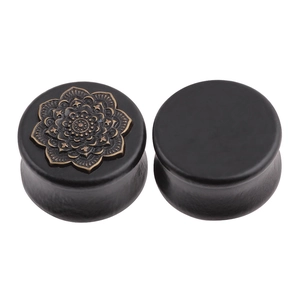 Detail of wooden ear plugs with vintage bronze mandala relief in bohemian style