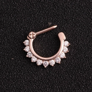 Rose gold septum ring with eleven clear zircons and cross pattern on black background