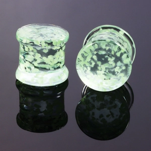 Leuchtende grüne Glas-Ohr-Expander mit Double Flare Design auf reflektierendem Grund