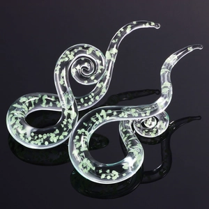 Spiralen-Ohrdehner aus Glas mit grünem Glitzer-Inlay auf spiegelndem schwarzem Hintergrund