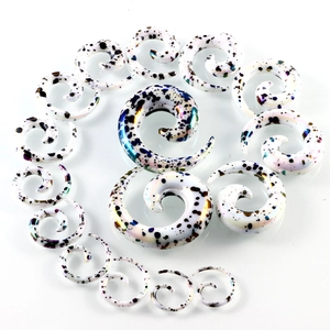 Makroaufnahme weißer Acryl-Spiralen-Ohrdehnersets mit blauem und lila Tinten-Spritzer-Muster