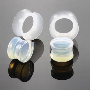 Macro detail of polished synthetic opal ear plugs and tunnels with iridescent finish