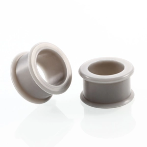 Detail view of light beige flexible silicone ear gauges with saddle plug design