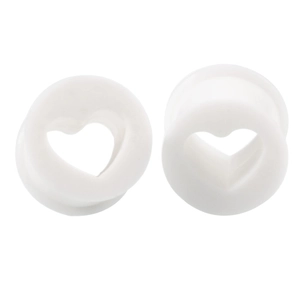 Macro view of white heart-shaped hollow ear plugs made of smooth silicone for ear stretching
