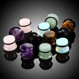 Macro view of assorted natural stone ear plugs with black rubber O-rings and smooth finish