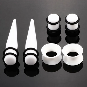 Detailliertes Set aus Acryl-Dehnstäben und Plugs mit schwarzen Silikonringen auf schwarzem Grund