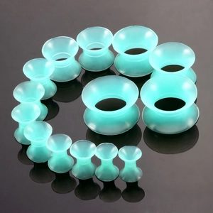 Makroaufnahme von mintgrünen Acryl-Ohr-Expander-Sets spiralförmig auf dunklem Hintergrund