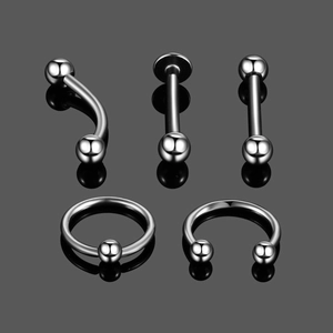 Macro view of assorted stainless steel body piercing studs and rings with mirror reflection