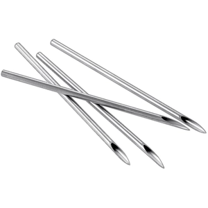 Close-up of four stainless steel piercing needles with sharp beveled tips on white background