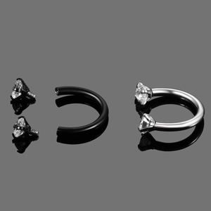 Detail of surgical steel horseshoe rings with screw-in zircon stones in black and silver