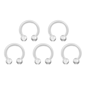 Close-up of five flexible transparent horseshoe piercing rings with screw-on balls