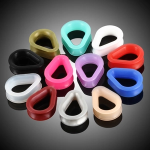 Macro shot of 12 colorful silicone teardrop ear gauges arranged in a circle on black background