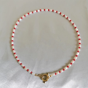 Detail of baroque freshwater pearls and red beads with a gold toggle clasp on silk fabric