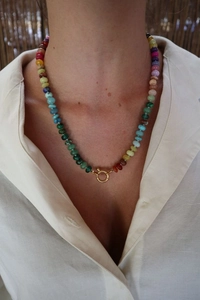 Close-up of a colorful natural stone necklace with a gold spring clasp on a model