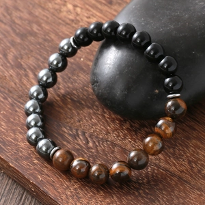 Men's natural tiger eye hematite obsidian beaded bracelet on dark stones with wood background