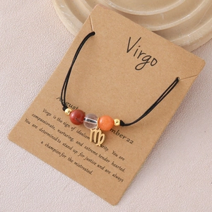 Detail eines Virgo Sternzeichen-Armbands mit Natursteinen und Goldanhänger auf Karte