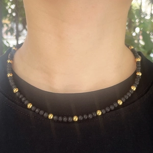 Minimalist beaded necklace with black lava stone and gold beads on a female model