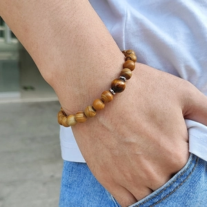 Natural peach wood and tiger eye stone beaded elastic bracelet worn on a wrist