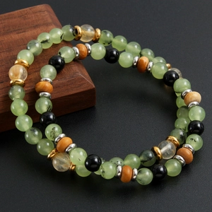 Natural prehnite and stone bead bracelet set with metallic spacers on dark wood