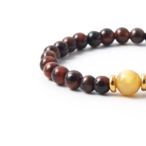 Red tiger eye stone beaded bracelet with amber accent and gold spacers on white background