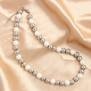 Detailed macro view of S.Steel lobster clasp and white pearls on champagne silk fabric