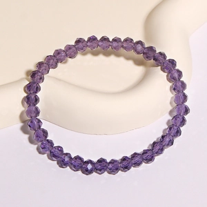 Makroaufnahme von facettierten lila Kristallglasperlen an einem elastischen Damenarmband