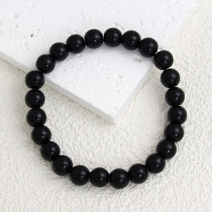 Vue macro de 21 perles en pierre naturelle noire polie de 8mm sur un bracelet élastique